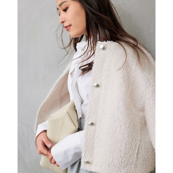 白のボウタイブラウスにジャケットを肩掛けした近藤千尋さん