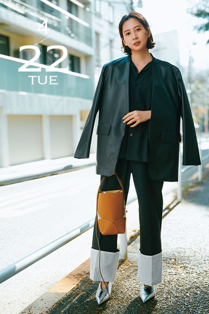 シャツとジャケットとパンツのオールブラックコーデにキャメルのバッグとシルバーのシューズで抜け感を出した着こなし