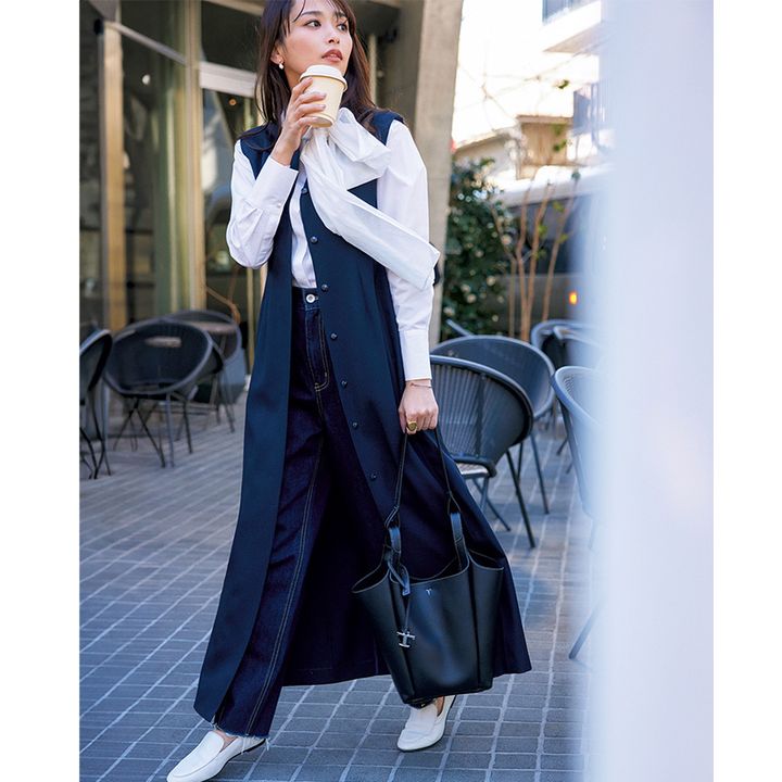 ボウタイブラウスと濃紺デニムにロングジレを羽織ってトッズのトートバッグと私物の白ローファーを合わせた近藤千尋さん