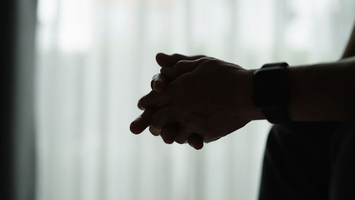 手を組んでソファに座っている人