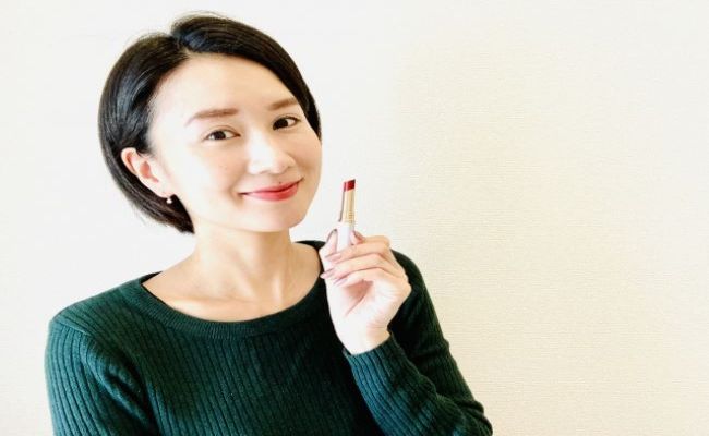 赤い口紅を持つ笑顔の女性