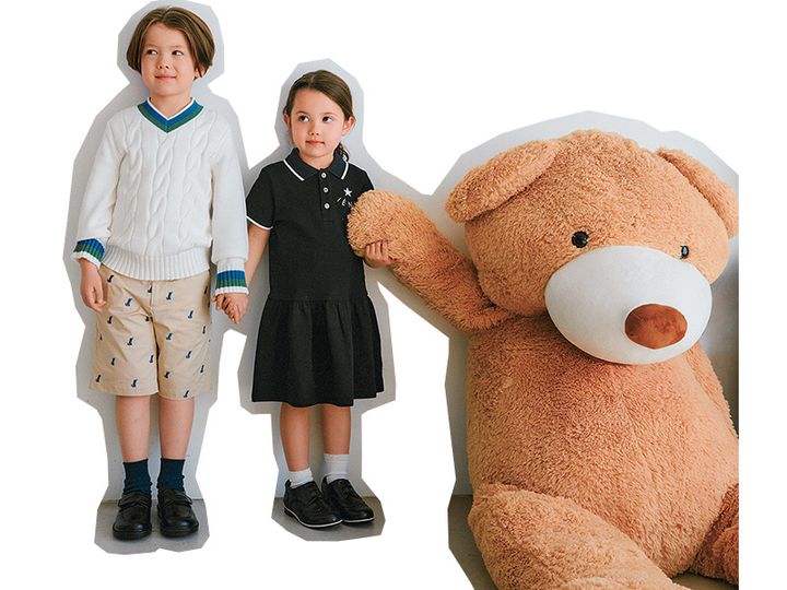 男の子と女の子がくまの大きなぬいぐるみと並んでいる様子