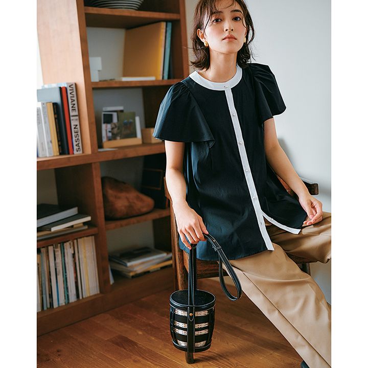 白ライン飾りの半袖黒ブラウスにベージュのパンツのコーデ