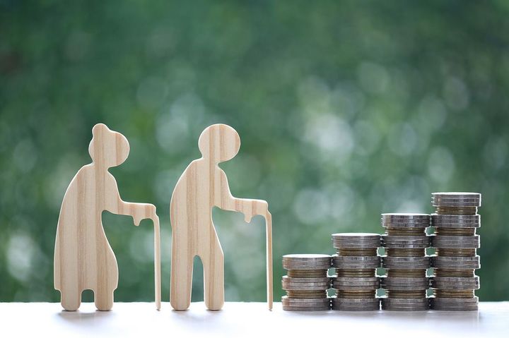 積まれたコインと高齢者の人形