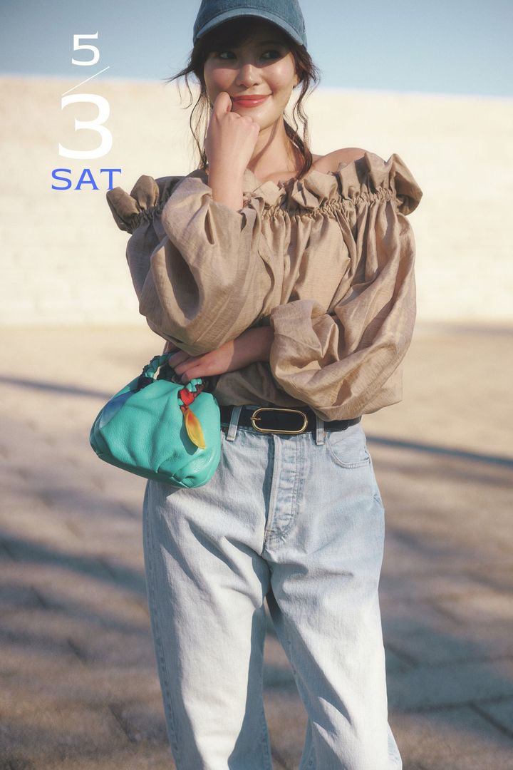 ブラウンのオフショルブラウスと薄色デニムにキャップやターコイズカラーのミニバッグを合わせたコーデ