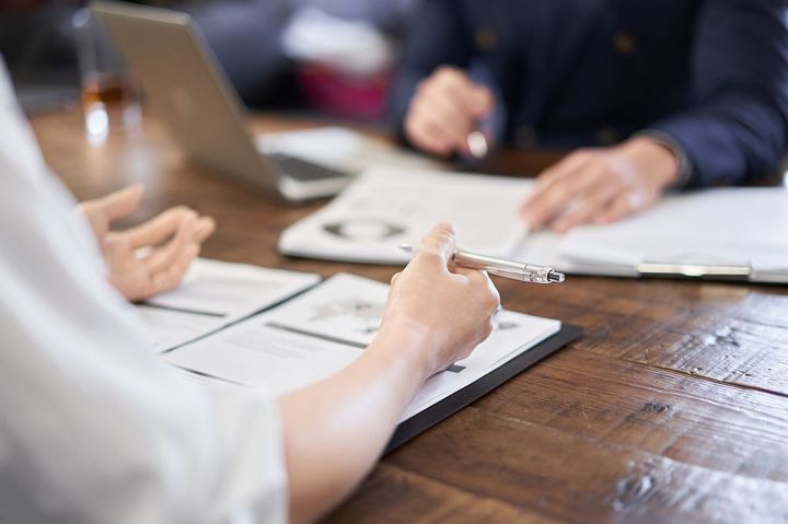 資料を広げて向かい合って話をするビジネスパーソン