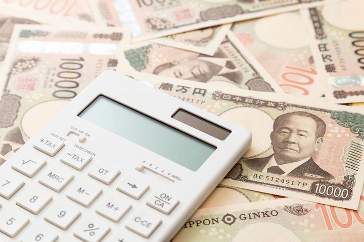 敷き詰められた一万円札の上に電卓