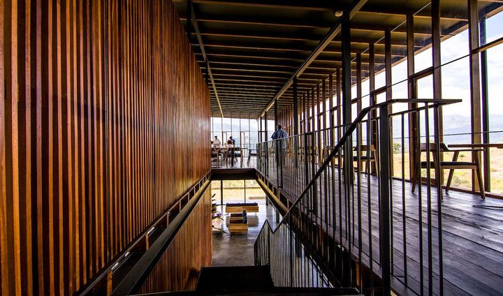 再生木材、スチール、コンクリートで構成され、周囲の木々と調和する洗練された建築デザイン。