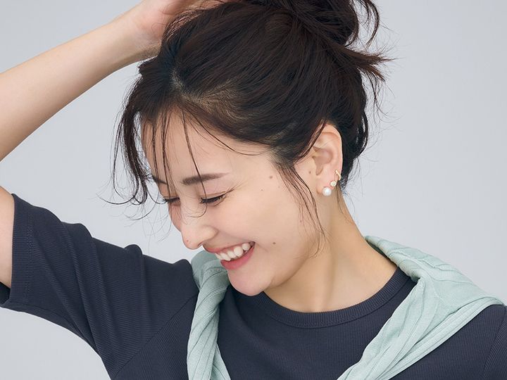 Tシャツにシャツを肩掛けしてまとめ髪した耳元に音符のダイヤピアスとパールピアスを重ねづけした原田夏希さん