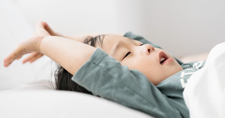 子どもが布団で寝転がっている様子