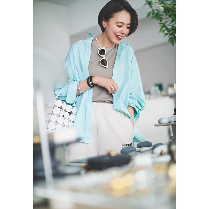 ベージュのTシャツとスウェットパンツにミラオーウェンの防シワ機能つきシャツを羽織った浅見れいなさん