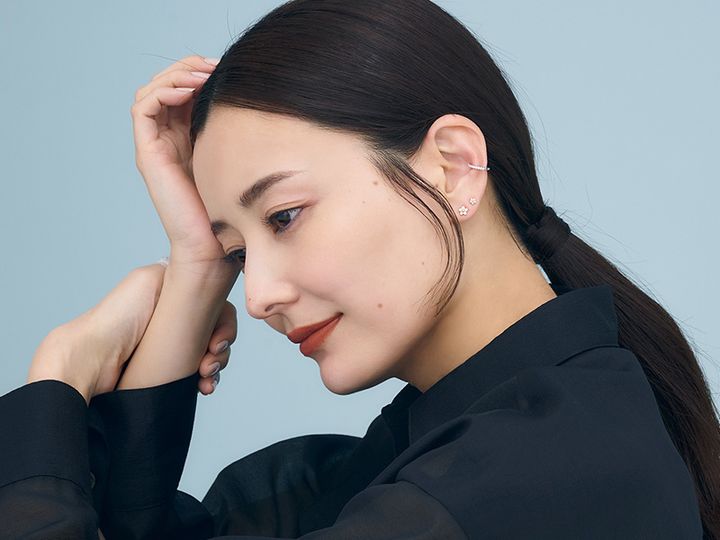 濃色のシャツを着てサイド髪を垂らしてひっつめた耳元にイヤーカフとピアスを重ねづけした原田夏希さん