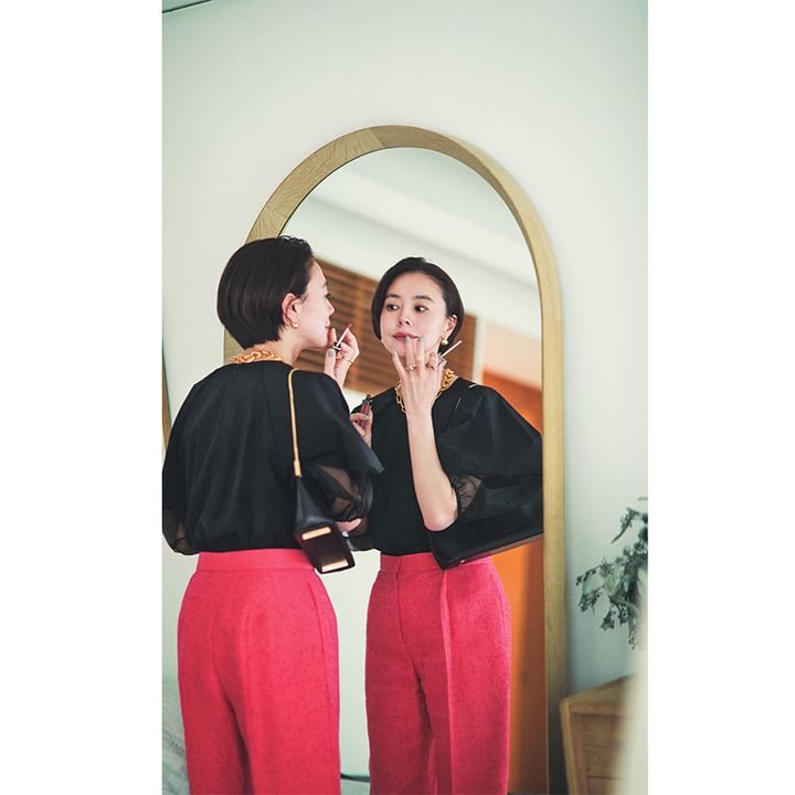 エレンディークの黒のシアーブラウスとカラーパンツを着てリップを塗る浅見れいなさん