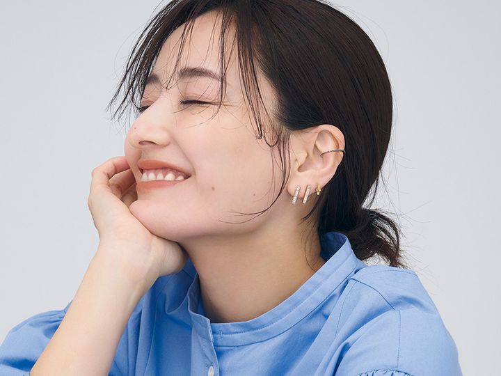ブルーのシャツを着てまとめ髪した耳元にイヤーカフとピアスを重ねづけした原田夏希さん