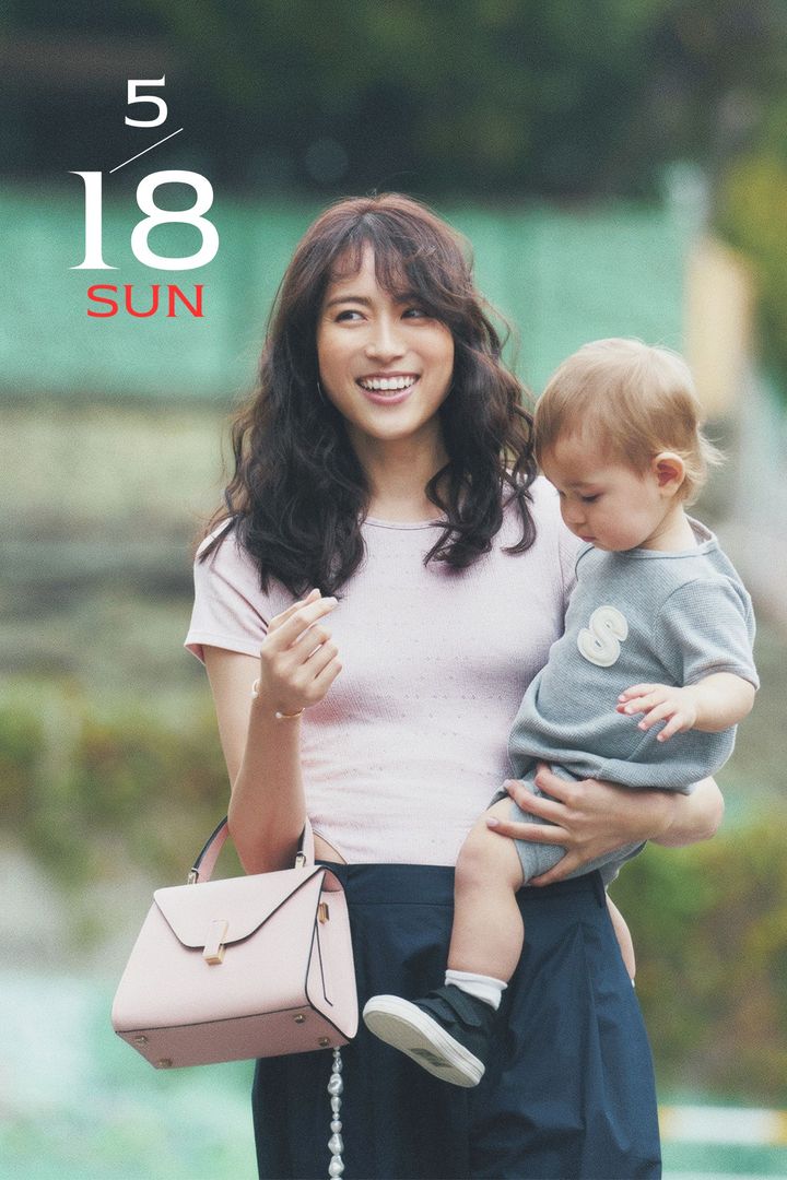 ピンクのボディスーツとネイビーパンツにピンクのハンドバッグを持って赤ちゃんを抱っこした笹川友里さん