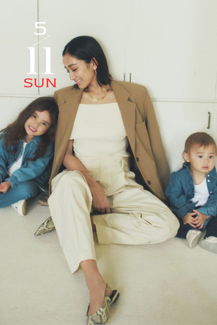 白のオフショルニットとパンツに茶色のジャケットを肩掛けしてパイソン柄のとんがりシューズを合わせたコーデ