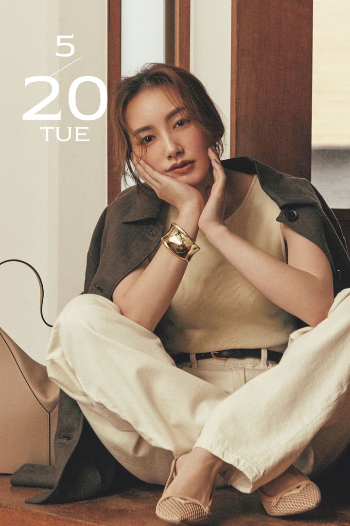 オフホワイトのトップスとパンツにブラウンのジャケットを合わせてベージュのバッグとシューズを合わせたコーデ