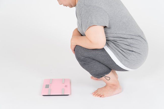 体重計の前にいるぽっちゃりした女性