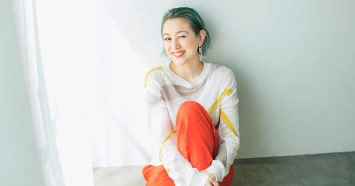 座って片膝を抱えて微笑むSHELLYさん