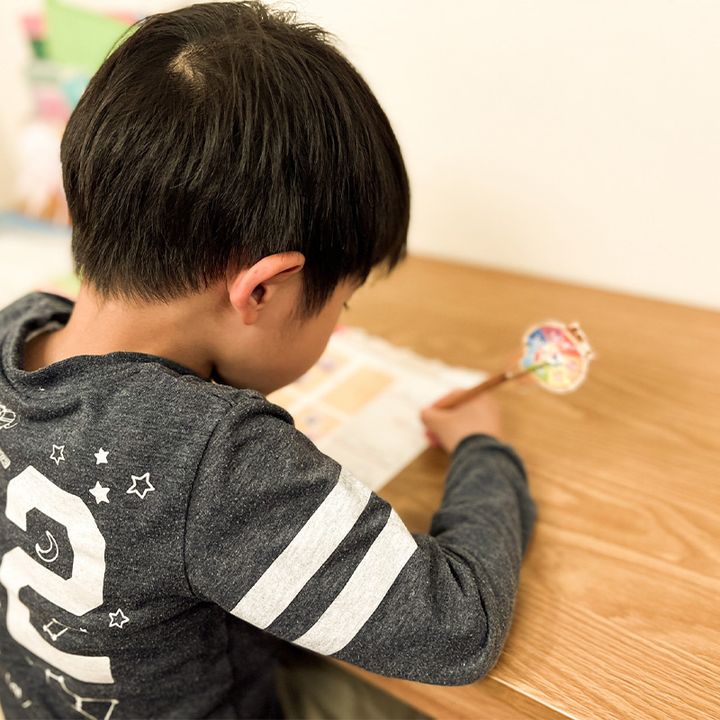 机に向かって鉛筆を持って字を書いている男の子