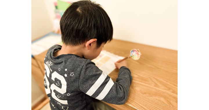 机に向かって鉛筆を持って字を書いている男の子