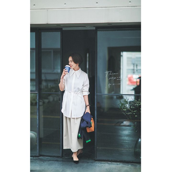 ルルウィルビーのポリエステル100％の腰にリボンがついた長め丈シャツにベージュのスカートを合わせたお仕事コーデ