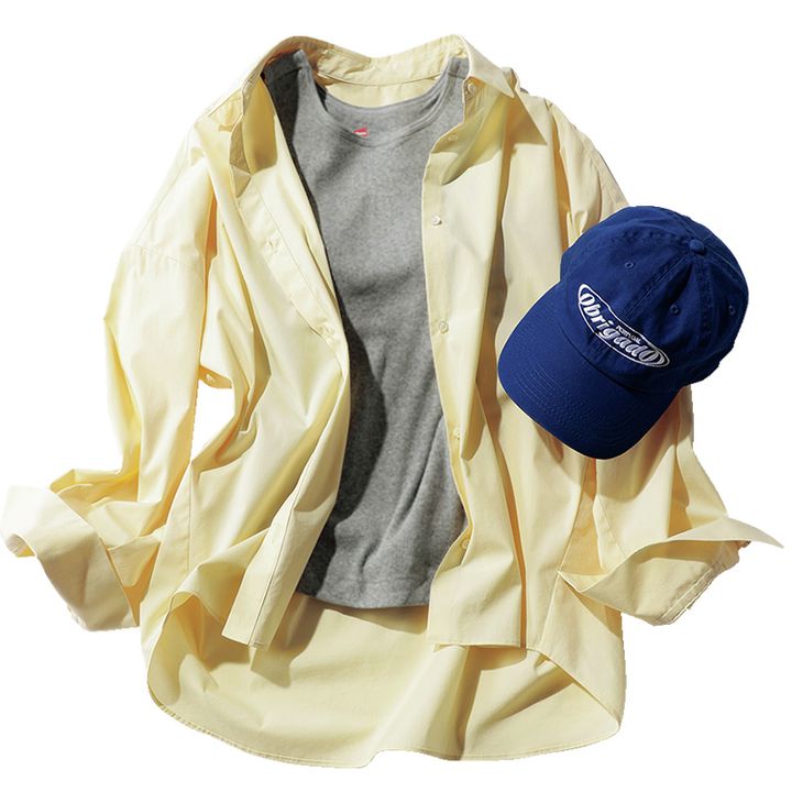 グレーのタンクトップにソージュの黄色のシャツとネイビーのキャップを合わせたコーデ