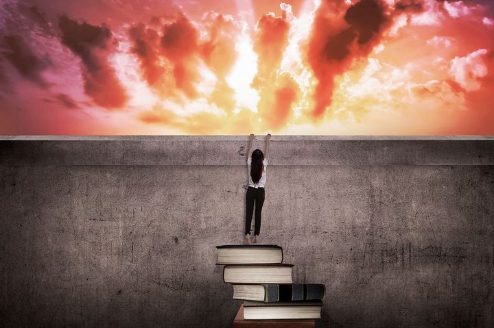 高い壁によじ登ろうとする女性