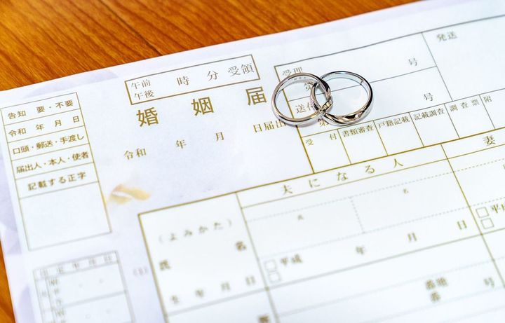 結婚届の上に置かれた一対のペアリング