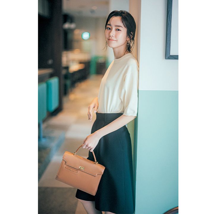 淡色の5分袖ニットとハーフパンツにキャメルのハンドバッグを持った桐谷美玲さん