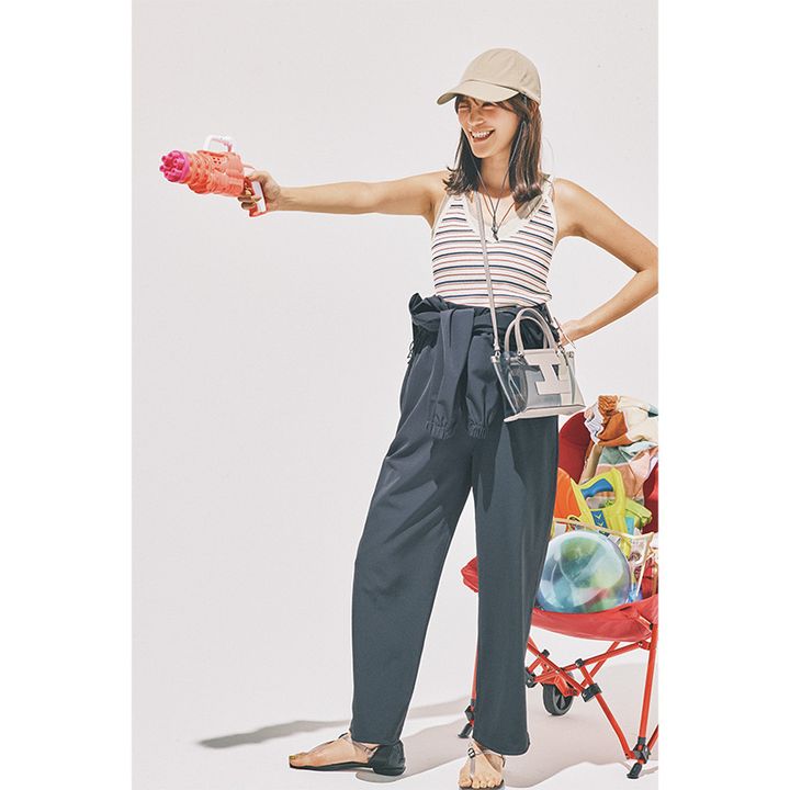 ボーダータンクトップにクラネのラッシュガード素材のジャンプスーツを上半身を脱いで腰で巻いてキャップやクリアバッグを合わせている咲和希さん