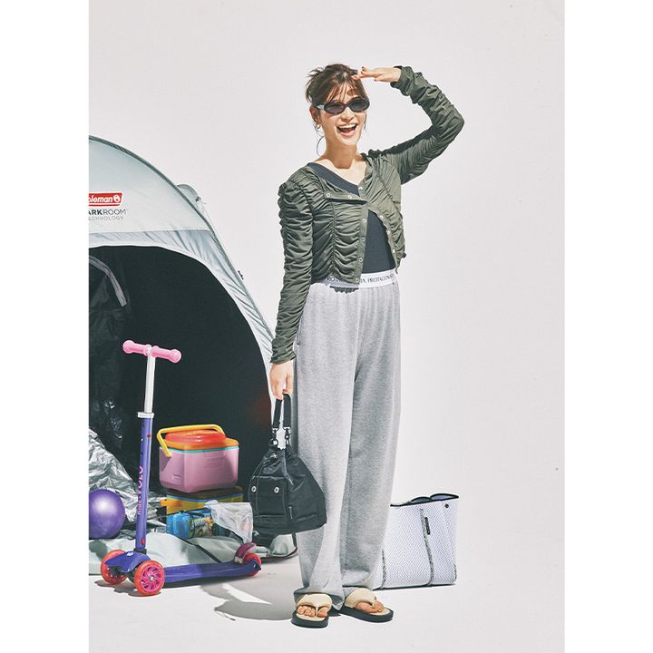 ワンショルダーのタンクトップとグレーのスウェットパンツにシャーリングデザインのカーキのカーディガンを着た咲和希さん