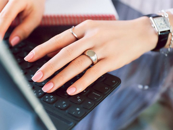 ペールピンクのマニキュアを塗った手でパソコンを打つイメージカット