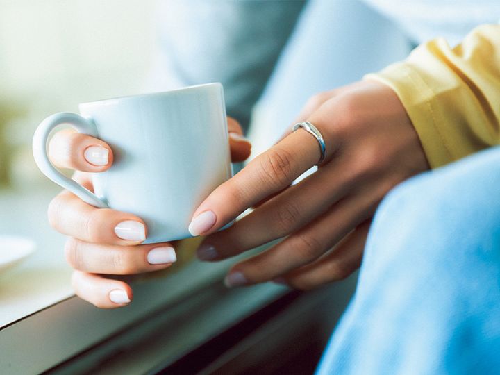 白いネイルを塗った女性がマグカップを持つイメージカット