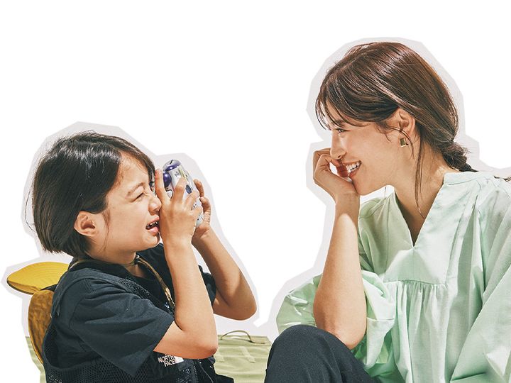 グリーンのボリューム袖ブラウスとスティックパンツにサンダルやキャップを合わせたママと写真を撮っている男の子