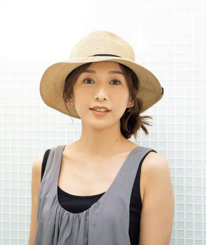 リゾートスタイルに寄り添うつば広の麦わら帽子には、サイドに寄せたラフなシニヨンが好相性。