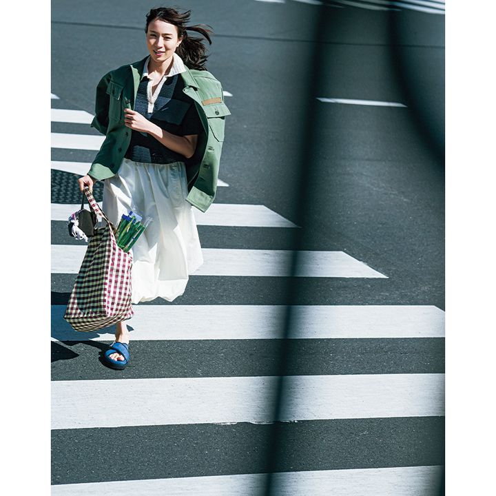 ポロニットと白スカートにミリタリージャケットを羽織ってダッシュする笹川友里さん