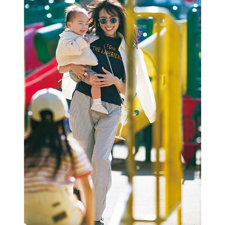 ロゴTとストライプパンツにショート丈の白シャツを羽織った公園コーデの笹川友里さん