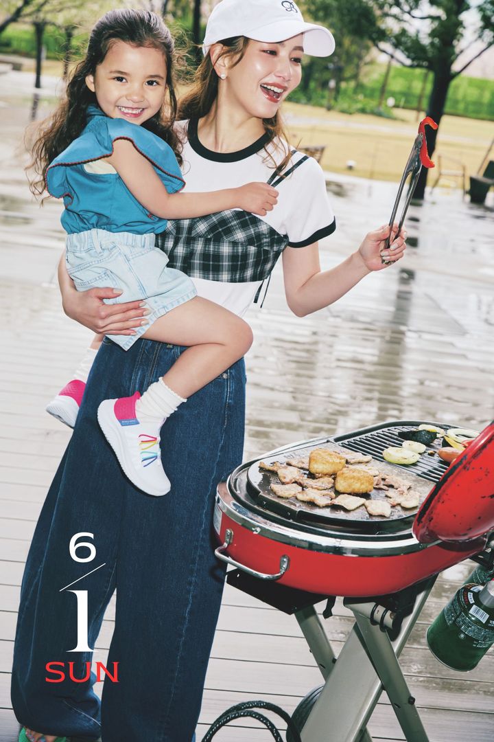 白Tシャツとデニムにチェック柄のビスチェを重ねて子どもを抱っこしながらBBQを楽しむ辻元舞さん