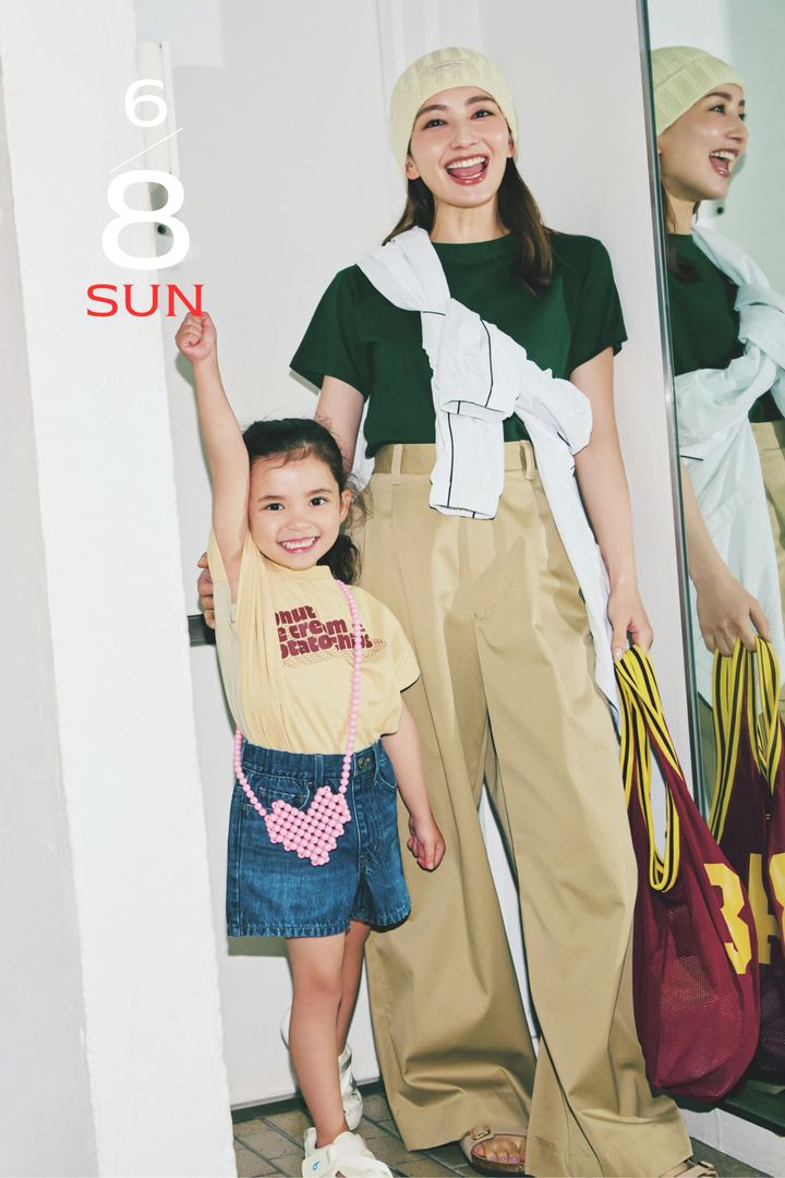 深緑のTシャツとチノパンにスポーティアウターを襷掛けしてニット帽やトートを持った辻元舞さんとロゴTシャツとデニムスカートにピンクのハート型のポシェットをかけた女の子