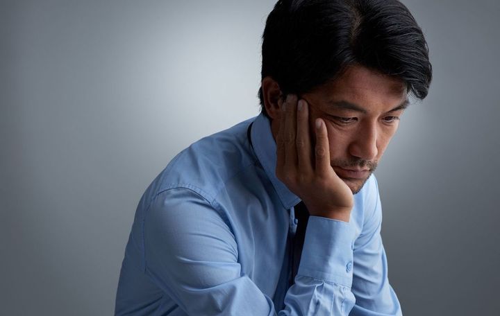 頬杖をついて悩ましげな表情をしている男性