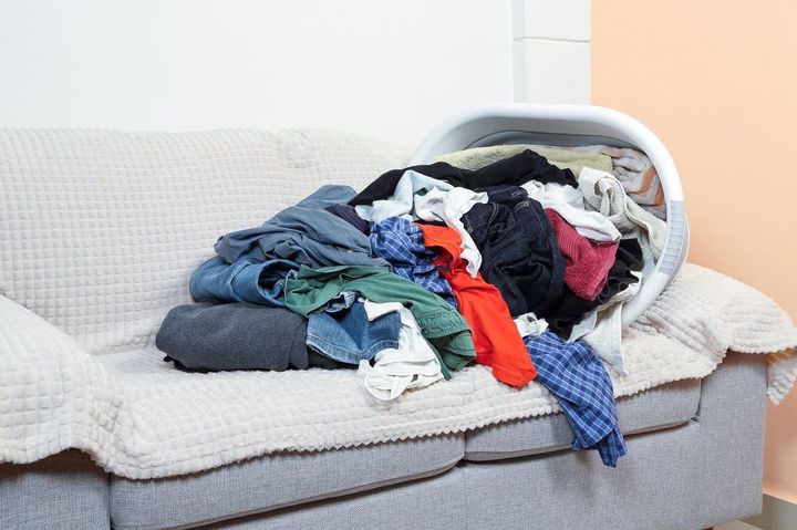 ソファーの上で洗濯物かごが横倒しになり、洗濯物があふれている