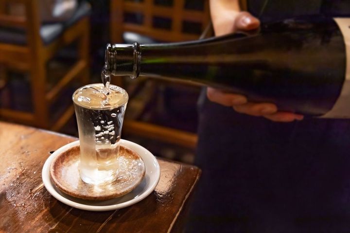 居酒屋で店員がよく冷えた日本酒を注いでくれている