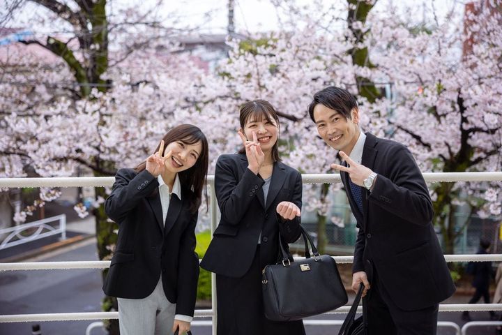 桜の前でピースサインを作るビジネスマン