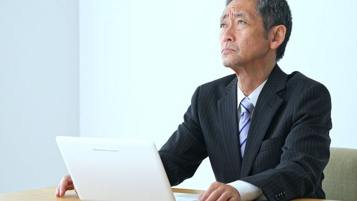 ノートパソコンの前で悩むビジネスマン