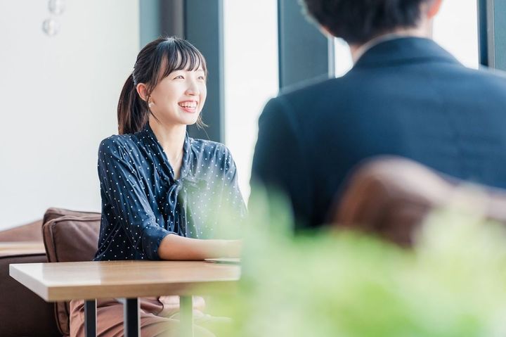 笑顔で話す女性と話を聞いている男性の後ろ姿