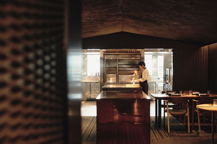 オープンキッチンでライトを浴びる稗田シェフ。見ている客も出演者の一部になる。Photo_ Hedy Chang