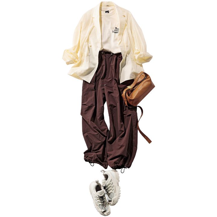 胸元にロゴが入ったTシャツと茶色のシャカパンツにジャケットを羽織ってサロモンのスニーカーや茶色のバッグを合わせたコーデ