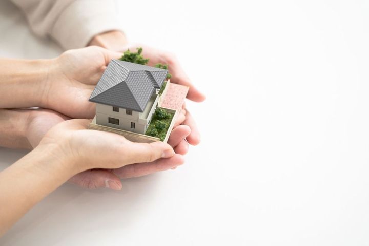 夫婦の手に置くミニチュアのマイホーム