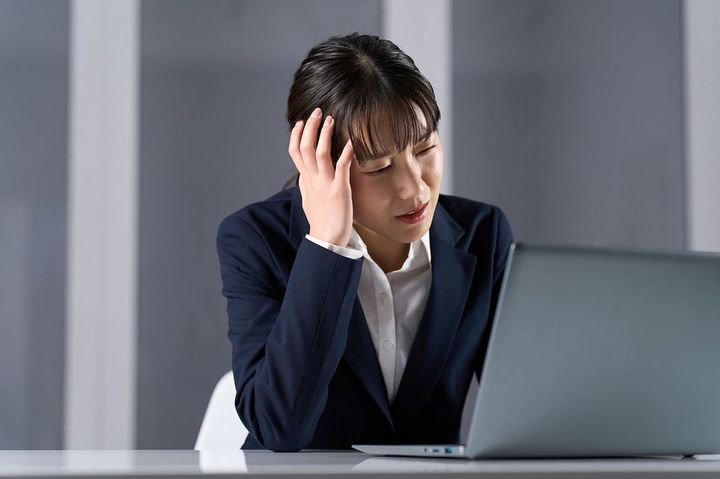 仕事をしながら頭を抱える女性